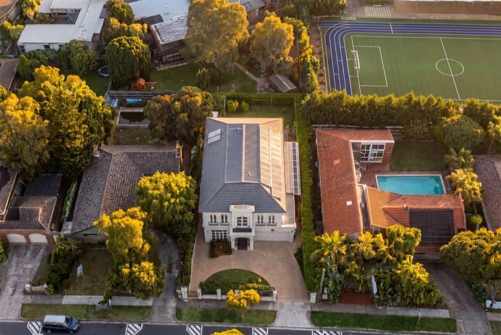A golden hour aerial of a two storey house and its garden